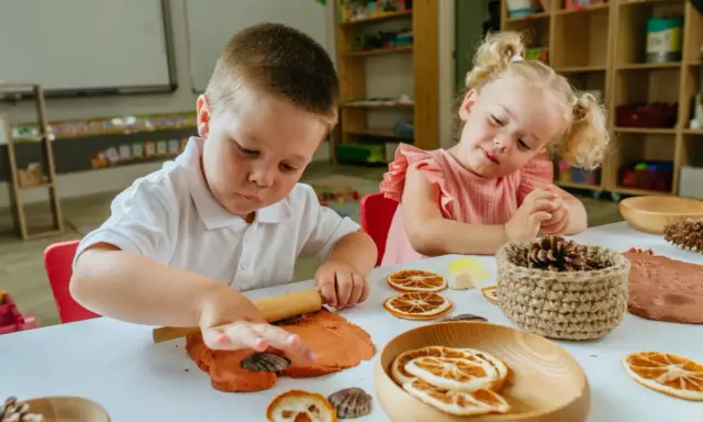 Niños de 3 a 4 años disfrutan de actividades creativas en casa, moldeando arcilla y decorando con elementos naturales.