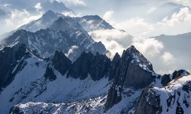 Majestatyczne Tatry Wysokie, ośnieżone szczyty i mgliste doliny tworzą zapierający dech w piersiach krajobraz.