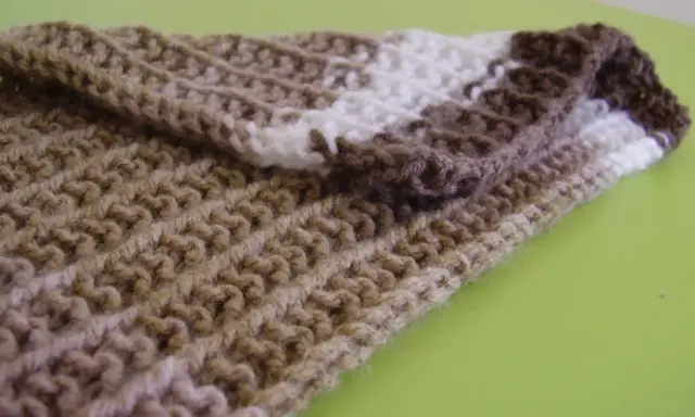 Bufanda tejida con patrones puntos reversibles a dos agujas, en tonos marrones y blanco.