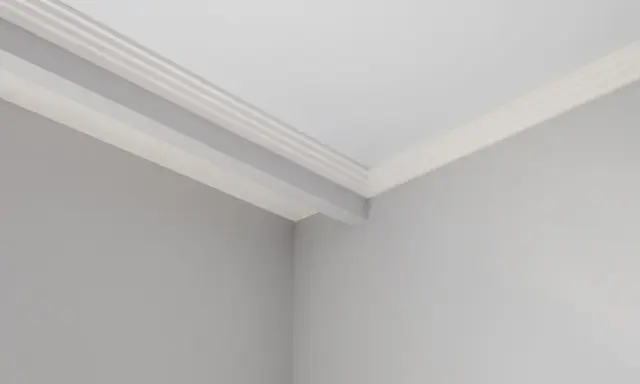Angolo di una stanza con pareti grigie e soffitto bianco. Si nota uno stacco tra parete e soffitto con una modanatura decorativa.