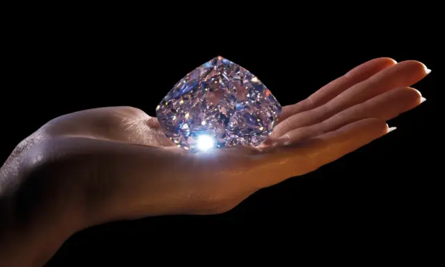 Mano che regge un enorme diamante scintillante, simbolo di eternità e amore. Il diamante significato è immenso.