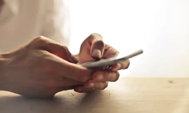 Dłonie trzymające telefon, jakby zastanawiając się, czy na odwyku można mieć telefon.