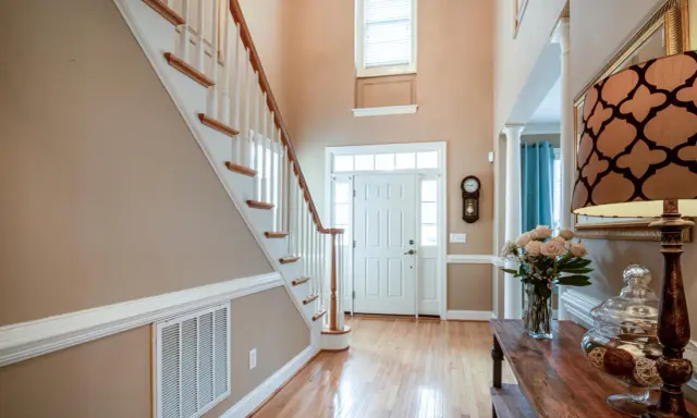 Pasillos con encanto: escalera de madera, puerta blanca y un jarrón con rosas.