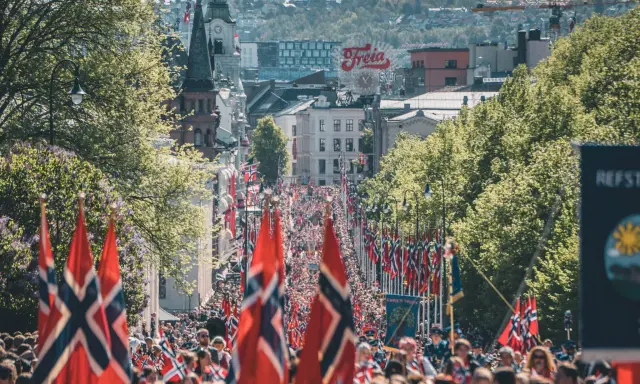Tłum ludzi na ulicy w Oslo, z norweskimi flagami. Czy Norwegia jest w NATO? Tak, jest członkiem od 1949 roku.