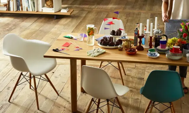 Tavolo in legno con sedie Eames House, cupcake, candele e fiori. Un'atmosfera accogliente per una festa.