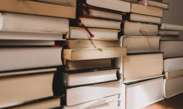 Pile di libri, alcuni con segnalibri rossi, pronti per essere letti. Ecco i miei ultimi libri consigliati.