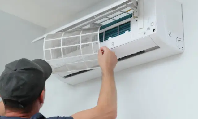 Un technicien retire un filtre sale d'une climatisation. Un entretien régulier est essentiel pour le prix et l'efficacité de votre climatisation.
