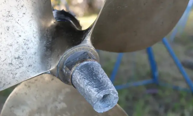 Gros plan sur l'hélice d'un bateau, montrant l'usure de l'anode et les détails gravés.