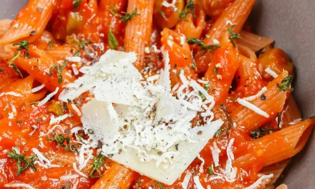 Szybki obiad z makaronem penne w sosie pomidorowym, posypany parmezanem i ziołami. Idealny na szybki posiłek.