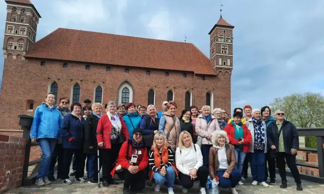 Grupa turystek pozuje na tle imponującego zamku biskupów warmińskich w Lidzbarku Warmińskim.