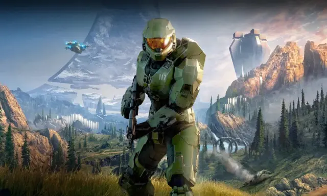 Master Chief w zbroi z Halo Infinite stoi na tle górskiego krajobrazu z pierścieniem Halo i pojazdem UNSC.