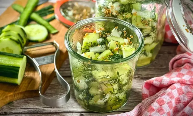 Schnellgurken rezept ohne kochen: Frische Gurkenscheiben mit Dill und Senfkörnern in Gläsern, bereit zum Einlegen.