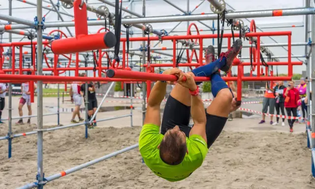 Mann hangelt sich kopfüber durch einen Hindernisparcours. Ein echter **obstacle run**!