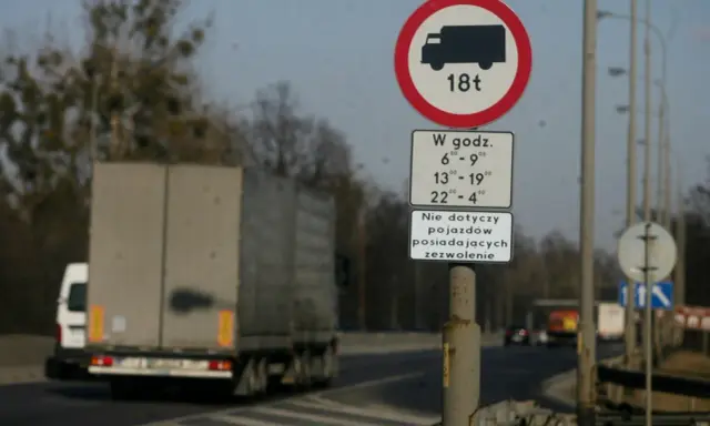 Znak zakazu wjazdu dla pojazdów o masie powyżej 18 ton w określonych godzinach. Czy tiry mogą jeździć w niedzielę? Zależy od zezwolenia.