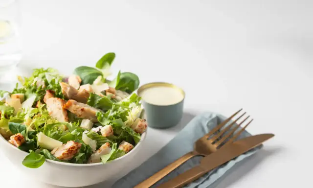 Salade César fraîche avec poulet grillé, croûtons et copeaux de parmesan, accompagnée de sa sauce crémeuse.
