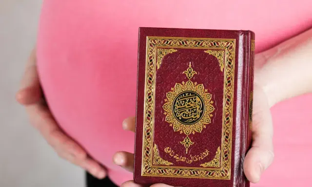 Schwanger, hält eine Frau den Koran. Im Islam gibt es Erleichterungen beim Fasten während der Schwangerschaft.