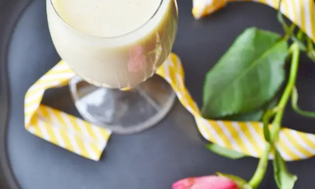 Kremowy likier bananowy w kieliszku, ozdobiony żółto-białą wstążką. Idealny na deser, jak z przepisu na likier bananowy.
