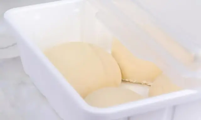 Pâte à pain trop fermenté dans une boîte blanche, prête pour la cuisson.