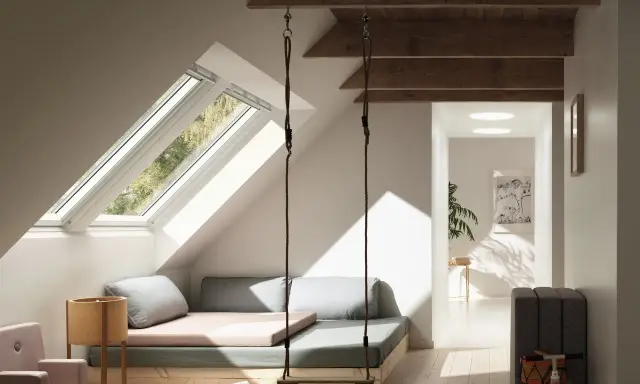 Aménagement comble 1m50 : un espace cosy avec balançoire, lit bas et vue sur la nature par les fenêtres de toit.