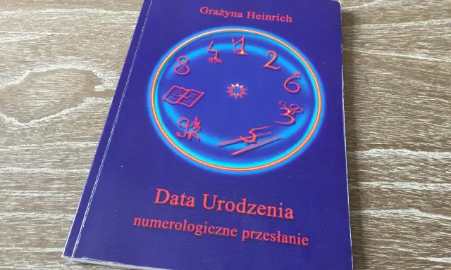 Okładka książki "Data Urodzenia numerologiczne przesłanie" Grażyny Heinrich. Centralny element to okrąg z cyframi i symbolami, sugerujący analizę liczby numerologicznej.