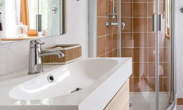 Bagno moderno con lavabo bianco, rubinetteria cromata e doccia con piastrelle color terra. Ideale per misure minime mini bagni piccoli progetti.