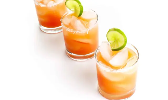 Drei erfrischende Salty Dog Cocktails mit Eis und Limettenspalten, bereit zum Genießen.