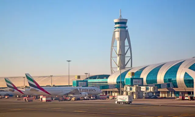 Emiraty Arabskie linie lotnicze na lotnisku w Dubaju. Samoloty Emirates, wieża kontroli lotów i nowoczesny terminal.