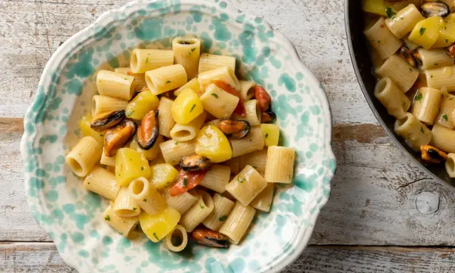 Un piatto di pasta patate e cozze, un classico della cucina italiana, servito in una ciotola decorata.