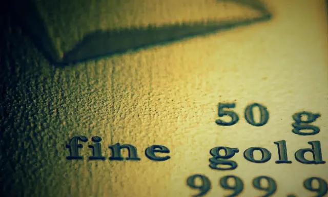 Zbliżenie na tekst "fine gold 50 g 999,9" wybity na powierzchni złota.