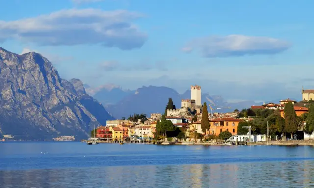Borgo sul lago di Garda con castello e montagne sullo sfondo. Un luogo incantevole da esplorare, scopri cosa vedere!