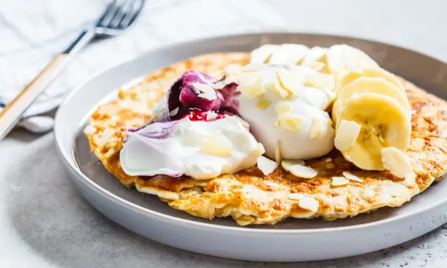 Puszysty omlet z jogurtem, jagodami, bananem i płatkami migdałów. Idealny przepis na zdrowy omlet na śniadanie.
