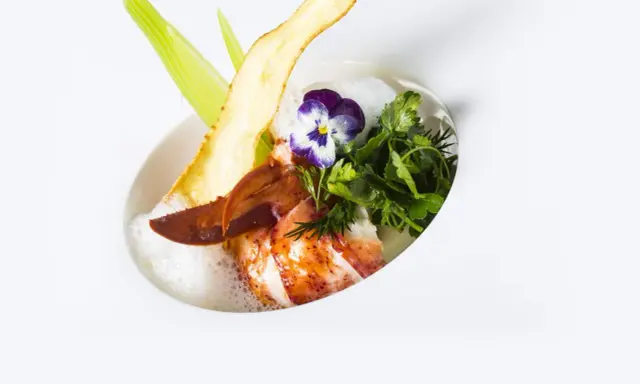 Homard poêlé, écume légère, chips de légume et fleur, une spécialité jurassienne raffinée.