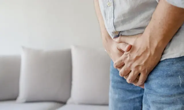Mężczyzna trzymający się za krocze, sugerujące problem z żylakami powrózka nasiennego. Rozważ tabletki na żylaki powrózka nasiennego.
