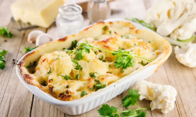 Un délicieux gratin de chou-fleur doré et gratiné, garni de persil frais, prêt à être dégusté.