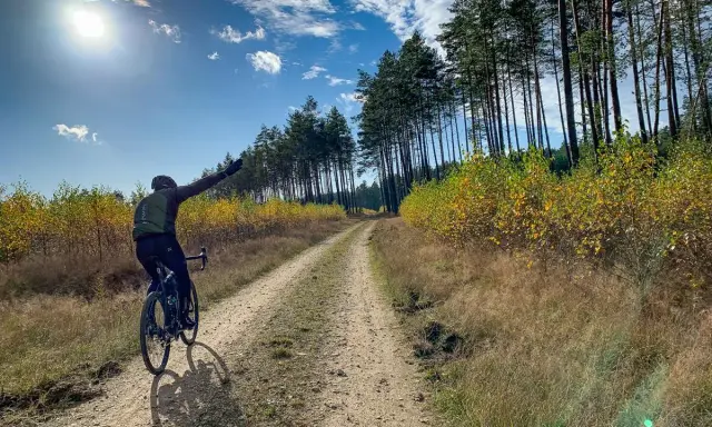 Rowerzysta na szutrowej drodze, cieszący się jesiennym krajobrazem. To prawdziwy gravel po łódzku, z dala od miejskiego zgiełku.
