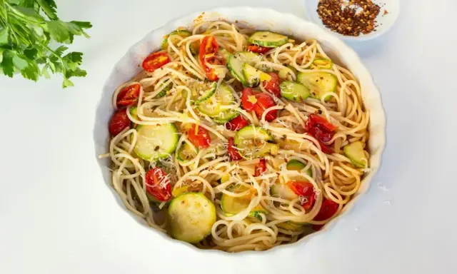 Pyszny makaron z cukinii, pomidorkami i parmezanem, gotowy do podania.