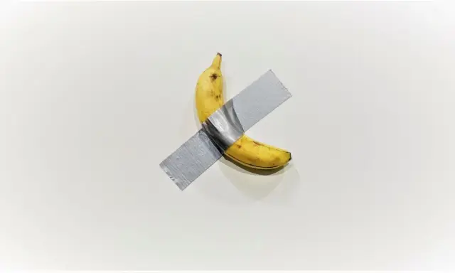 A ripe banana, a symbol of Maurizio Cattelan's art, is taped to a white wall.