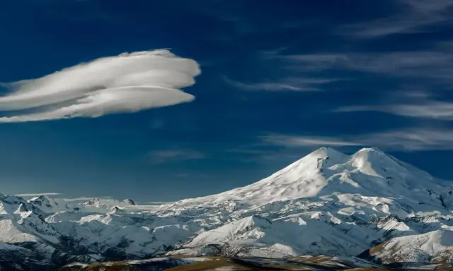 Elbrus szczyt w chmurach lenticularnych. Majestatyczne, ośnieżone góry pod błękitnym niebem.