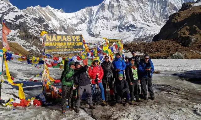 Grupa turystów na tle Annapurny podczas trekking w Nepalu. W tle majestatyczne, ośnieżone szczyty i kolorowe flagi modlitewne.