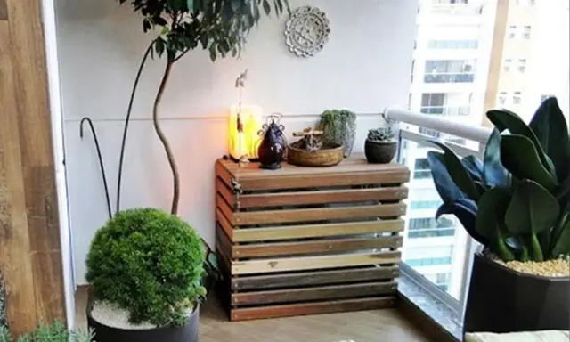 Mueble de madera para camuflar aire acondicionado exterior, decorado con plantas y objetos.