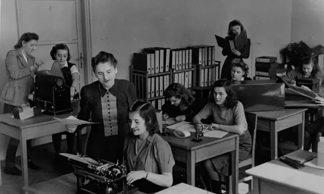 Kobiety pracujące w biurze, jedna przy maszynie do pisania, inne nad dokumentami. To właśnie tajne komplety, czyli tajne nauczanie, które odbywało się w ukryciu.