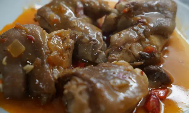 Manitas de cerdo en salsa, un plato de comida típica de Valladolid, con trozos de pimiento y cebolla.