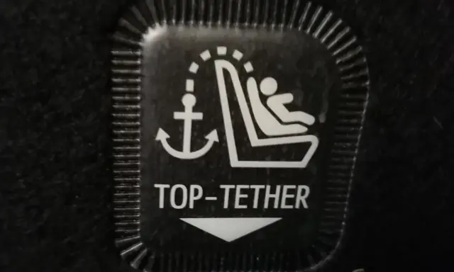 Symbol mocowania fotelika ISOFIX z kotwicą i dzieckiem. To jest oznaczenie TOP TETHER.