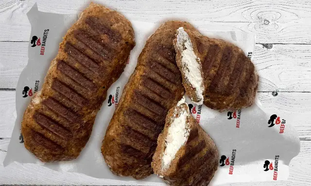 Gegrillte Bifteki, eines davon aufgeschnitten, zeigt eine cremige Füllung. Perfekt, um Bifteki selber machen zu lernen!