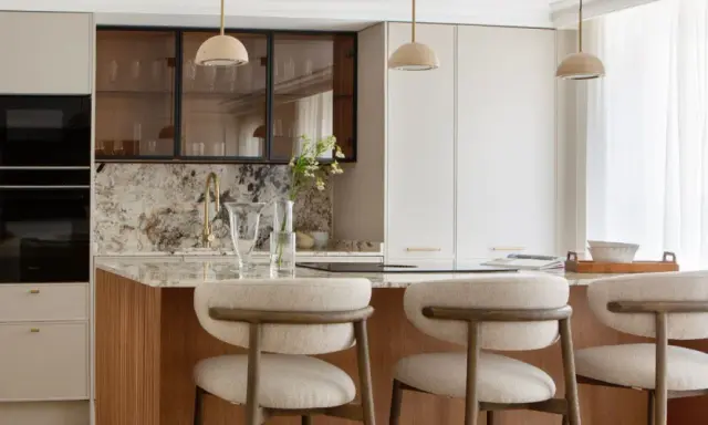 Cocina moderna con isla central, taburetes y electrodomésticos integrados. Un diseño atemporal que combina funcionalidad y elegancia.