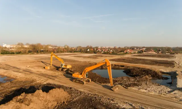Excavadoras trabajan en un sitio de remediación de suelos, moviendo tierra y agua para restaurar el terreno.