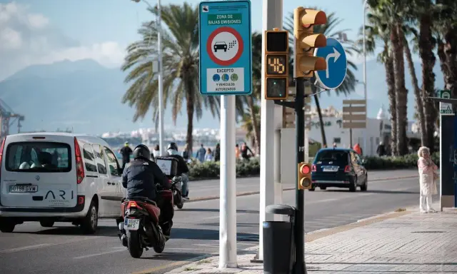 Señal de zona de bajas emisiones en Vigo. Coches y motos circulan bajo palmeras.