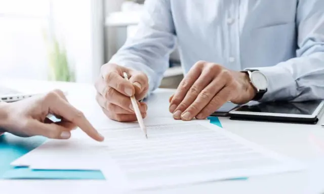 Due mani esaminano un documento, una indica un punto mentre l'altra tiene una matita, forse per la dichiarazione di inizio attività.