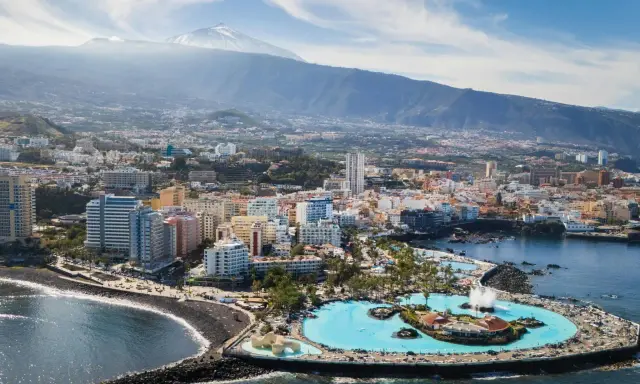 Puerto de la Cruz atrakcje: Lago Martianez, baseny z wodą morską, plaża, miasto i wulkan Teide w tle.