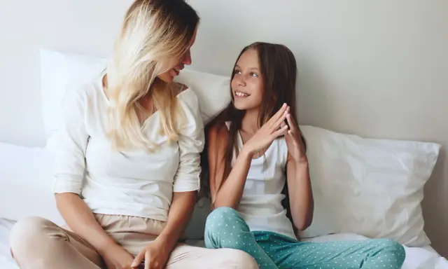 Mama i córka rozmawiają na łóżku. To świetny sposób na to, jak spędzać czas z 10 latkiem, budując więź i zrozumienie.